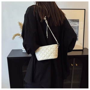 Detailed view of beige quilted chain bag with elegant rhombus pattern stitching