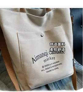 Close-up of off-white canvas tote bag featuring brown strap and silver metal snap button