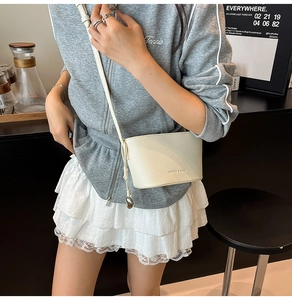Detailansicht der cremefarbenen Mini-Beuteltasche mit Litschi-Struktur und Metallkugel-Anhänger