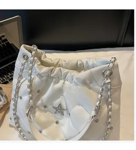Detail of white quilted bucket bag featuring star studs and silver chain strap