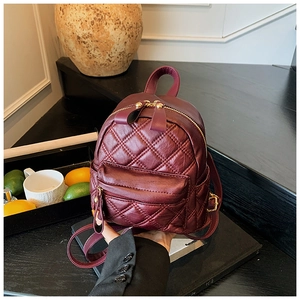 Detailed view of wine red quilted mini backpack with gold zippers and hardware