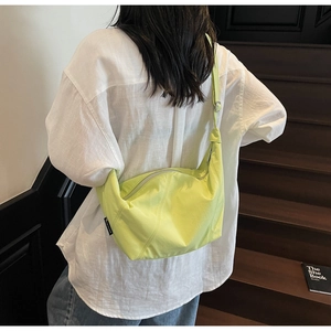 Detail der neongrünen Umhängetasche aus Nylon, getragen von einem Modell in Freizeitkleidung