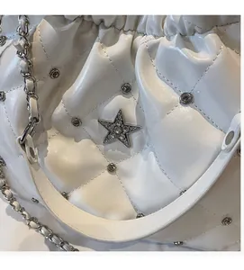 Close-up of white quilted leather texture with rhinestone star and chain strap detail