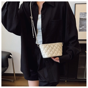 On-body view of a white quilted crossbody bag with a silver chain strap and knot detail
