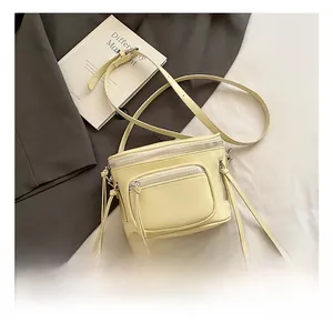Détail du sac seau en cuir jaune avec plusieurs fermetures éclair et longs glands