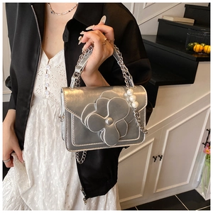 Silver handbag featuring 3D camellia flower and pearl chain handle in modern interior