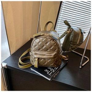 Close-up of olive green quilted backpack with leather bow and gold-tone zippers