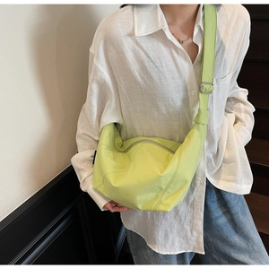 Detail der hellgrünen Halbmond-Nylontasche, die von einem Model im Freizeitstil getragen wird