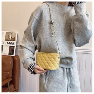 Detail of yellow quilted chain bag with adjustable gold ball buckle on leather strap