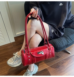 Detail of red bowling bag with heart charm shown on a dark corduroy sofa