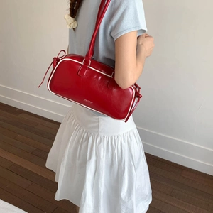 Detailed view of red bow baguette bag with white contrast piping and branded lettering