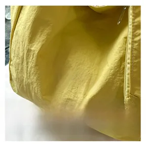 Macro view of a yellow nylon tote bag featuring white artistic lettering and precise stitching