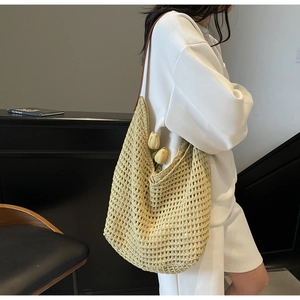 Detail of light yellow knit tote bag with hollow crochet texture and brown leather strap