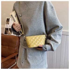 Detail view of a yellow quilted crossbody bag with adjustable gold metal chain strap