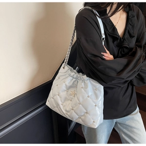Close-up of light blue quilted chain bag with star rhinestone and silver rivets details