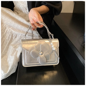 Detail of silver crossbody bag with a large camellia flower and pearl chain handle
