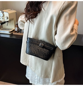 Dettaglio borsa a tracolla intrecciata nera con fibbia argento e blazer beige