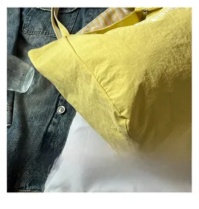 Close-up of bright yellow tote bag showing textured fabric and yellow white striped straps