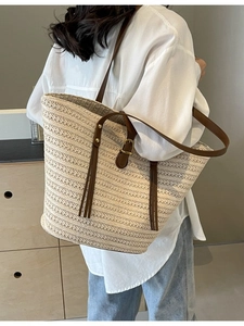Large woven straw tote bag with brown leather straps and stylish tassel for summer fashion