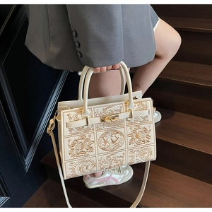 Macro shot of cream embroidered handbag with golden hardware and intricate motifs