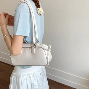 Detail view of bow tie decoration on a creamy white faux leather baguette shoulder bag