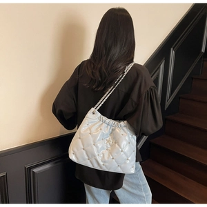 Détail du sac seau matelassé avec clous étoiles et chaîne porté par un mannequin