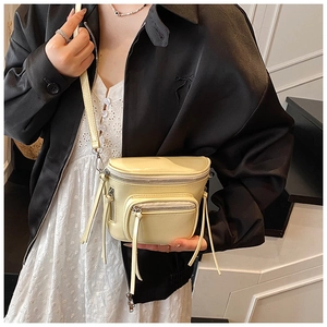 Détail d'un sac bandoulière beige avec de longues franges et plusieurs fermetures