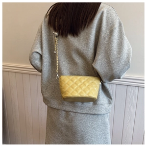 Detail of yellow quilted chain bag showing the metallic strap and premium leather texture