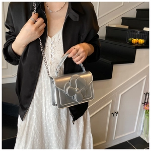 Detail of silver crossbody bag featuring a 3D camellia flower and metal chain strap