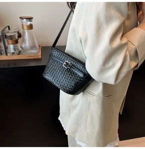 Dettaglio della borsa a tracolla nera intrecciata con fibbia in metallo su modella