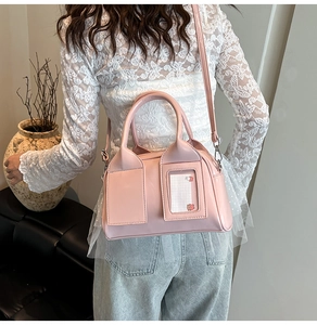 Detail view of a pale pink patent leather Boston bag styled as a crossbody bag on a model