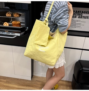 Bright yellow nylon tote bag with pleated texture and side view on a female model