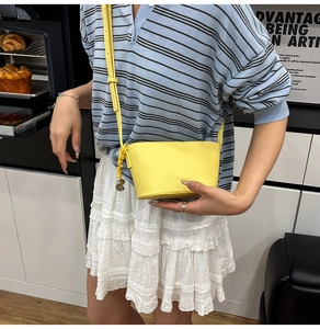 Modische hellgelbe Beuteltasche aus strukturiertem Leder mit Herzanhänger und Schultergurt