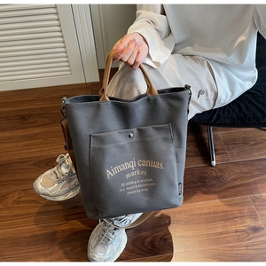Detail of dark grey canvas tote bag with metal snap button pocket and brown strap