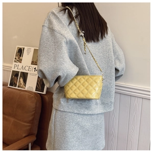 Detail of yellow quilted leather handbag with gold chain strap and metal adjustment ball