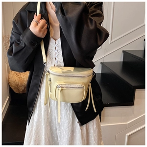 Détail d'un sac bandoulière beige à poches multiples avec zips argentés et sangle