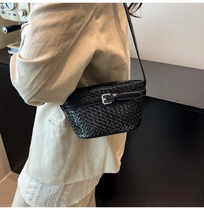 Dettaglio di una borsa a secchiello in pelle intrecciata nera indossata da una modella