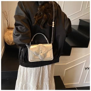 Detail of silver metallic floral crossbody bag with pearl chain shown on a model