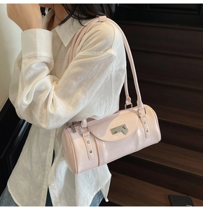 Detail of light pink cylindrical shoulder bag with heart lock on dark wooden stairs