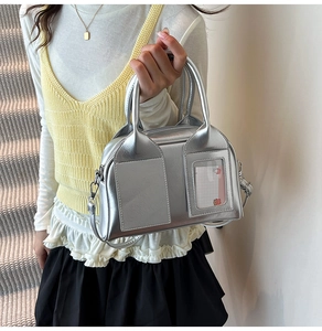 Fashionable silver metallic Boston handbag with adjustable shoulder strap on model