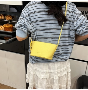 Detailansicht der gelben Mini-Beuteltasche aus Leder mit Litschi-Muster und Markenprägung