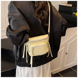 Détail d'un petit sac seau jaune avec franges latérales et bandoulière sur le mannequin