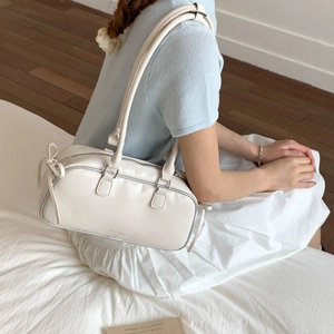 Lifestyle shot of a cream leather baguette bag with a side bow and silver details