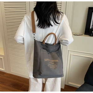 Detail of dark grey canvas tote bag with adjustable brown shoulder strap and front pocket