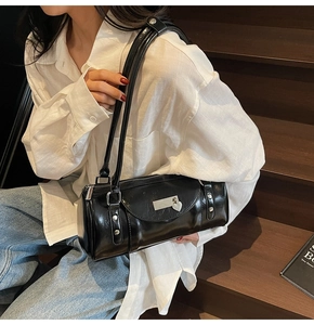 Detail of black glossy bowling bag with heart charm and rivets worn by a model