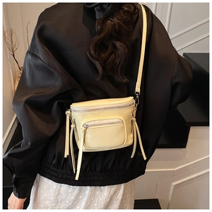 Détail d'un sac seau en cuir crème avec de longs glands et des poches zippées modernes