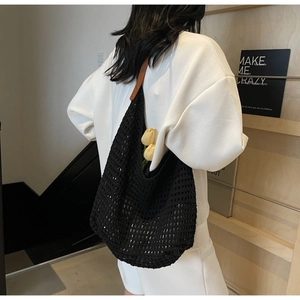 Detail of black hollow-out crochet tote with brown leather strap and mesh knitting