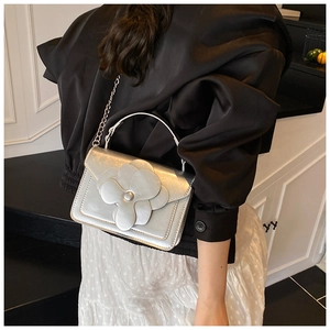 Detail of 3D silver flower on glossy square crossbody bag with metal chain strap