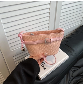 Dettaglio borsa a tracolla intrecciata rosa con fibbia decorativa e ciondolo a campana