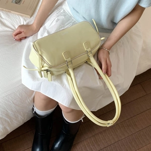 Close-up of pale yellow leather baguette bag with dual handles and smooth matte finish